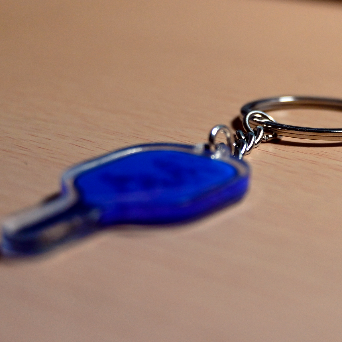 Blue keychain with a metal ring on a beige surface