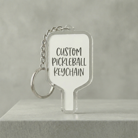 Clear pickleball keychain with text on a gray background