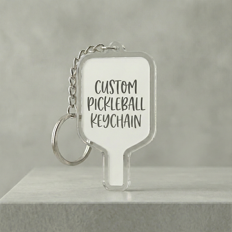 Clear pickleball keychain with text on a gray background