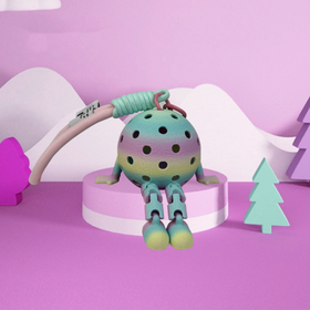 Colorful toy with a polka dot design on a pink platform against a light purple background