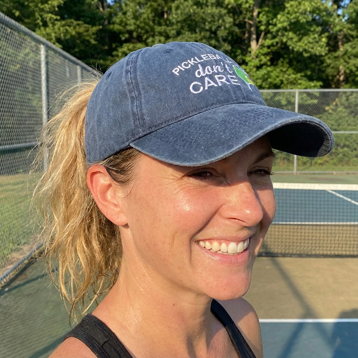 Woman wearing a blue cap with text on a tennis court